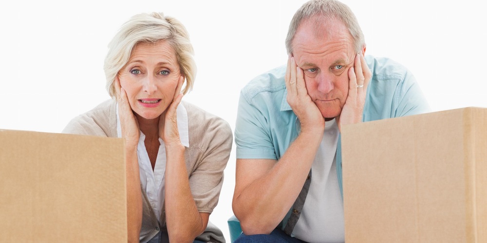 A couple in their 60s staring at cardboard boxes and getting started to declutter