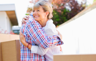 a couple in their 60s hugging each other after downsizing their home with moving boxes