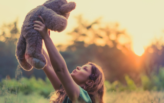 An image of a little girl holding her teddy bear that means a lot to her but is ready to let go.
