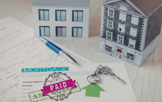 Paid mortgage document with house models and keys representing the milestone of being mortgage-free and the next chapter of life after 50.