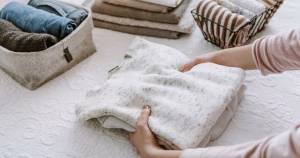 Midlife woman sitting on floor surrounded by moving boxes feeling overwhelmed while downsizing her home.