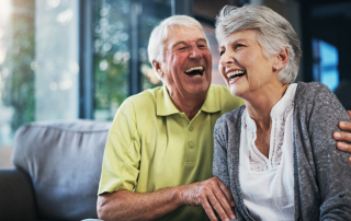 Happy older couple laughing together at home, representing freedom, simplicity, and enjoying life after downsizing.