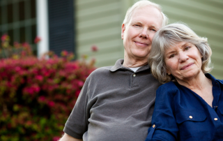 Peaceful older couple sitting outside their home during an empty nest stage, symbolizing reflection, downsizing decisions, and a new chapter of life.