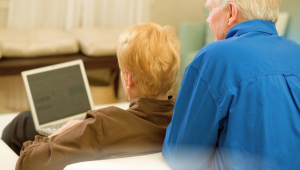 Baby boomer couple learning to use a laptop at home, embracing technology and AI in retirement lifestyle