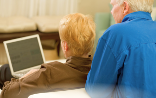 Baby boomer couple learning to use a laptop at home, embracing technology and AI in retirement lifestyle