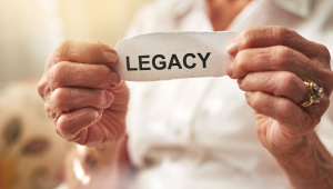 An older woman holding a paper that says "legacy".