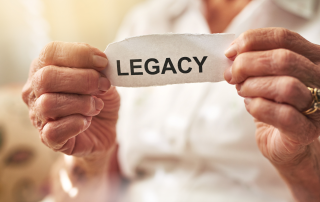 An older woman holding a paper that says "legacy".