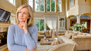 Older woman looking thoughtful while standing in a large, elegant living room, reflecting on whether her home still fits her current stage of life.